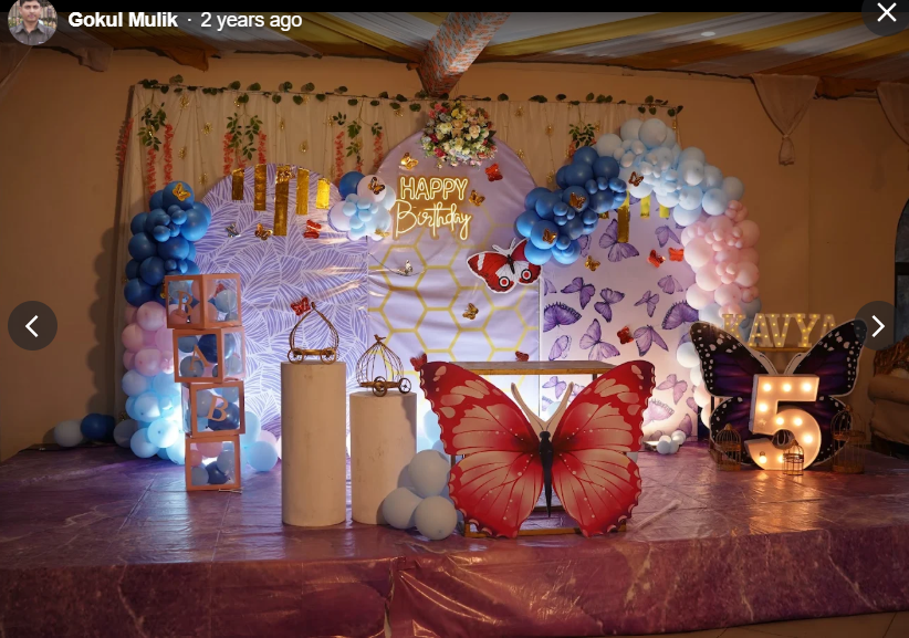 Butterfly themed birthday stage with oversized red butterfly prop